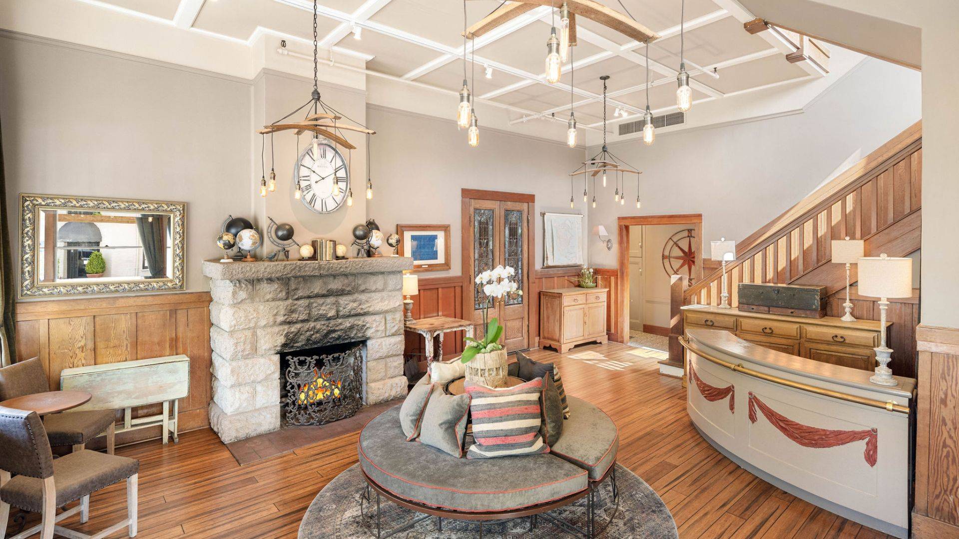 Bright and elegant front room of a home with fireplace, round bench seat, reception counter, hanging lights